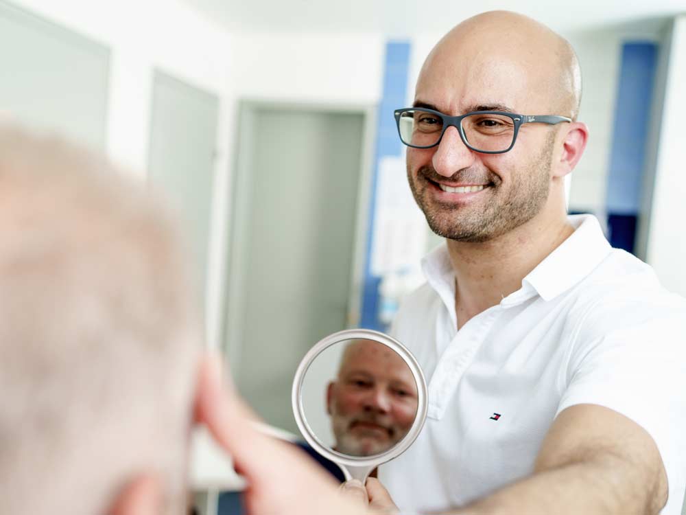 Nasen-OP Stuttgart - Dr. Maneschi zeigt Patienten das Ergebnis der Nasenkorrektur im Spiegel